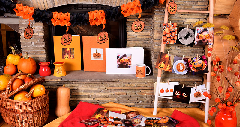 Composición de fotoproductos de Colorland para Halloween (fotolibros premium, tazas, insta fotos) en la chimenea.