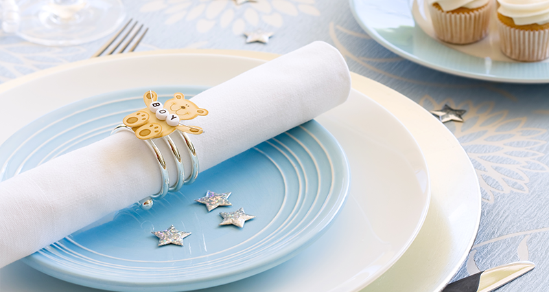 A napkin with a bear pin, placed on a blue plate