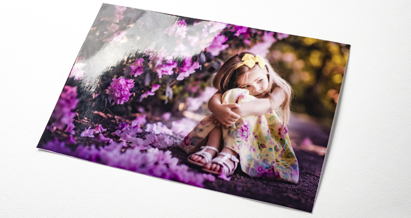 Fotka dievčaťa vedľa ker s fialovými kvetmi - fotka na lesklom papieri.