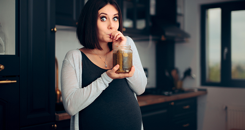 Těhotná žena se sklenicí okurek