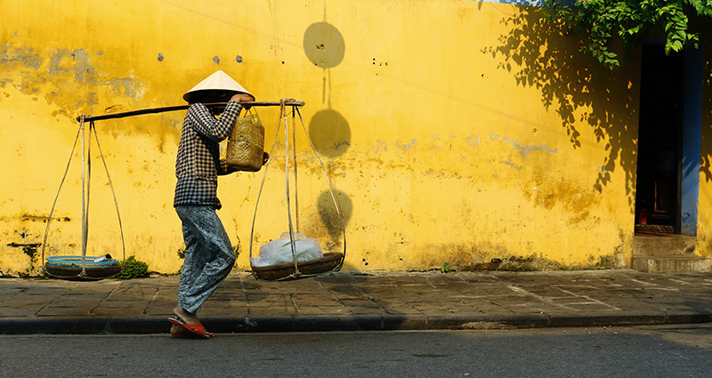 A working man wearing a traditional Vietnamese hat.