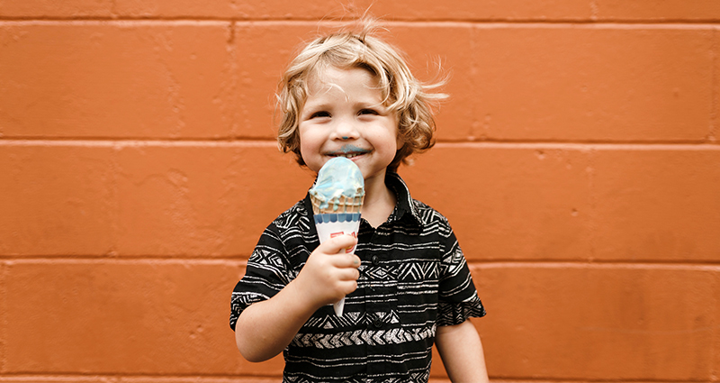 Niño comiendo helados en el centro de la foto.
