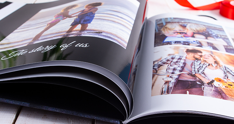 Detailní záběr na otevřený starbook s fotografiemi zamilovaného páru od dětství až po současnost.