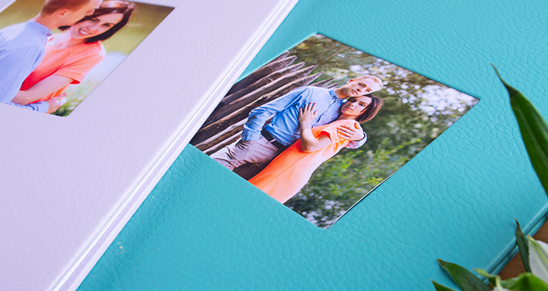 Close up on two Photo Books Exclusive with eco leather cover and pictures of a couple in photo slots, delicate flowers next to it.