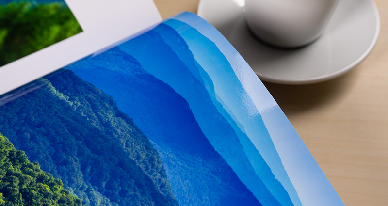 Close-up on a photo of blue sky shades printed in a Starbook. A white cup on a coffee table next to the book.