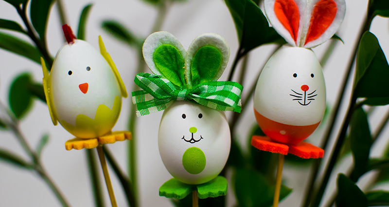 Easter decorations on sticks. Green plant in the background.