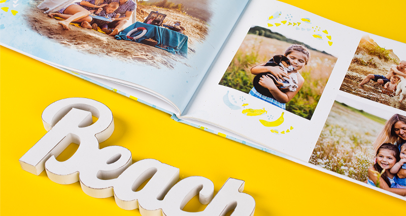 Family holiday photobook landscape placed diagonally with wooden letters creating the word BEACH below it.