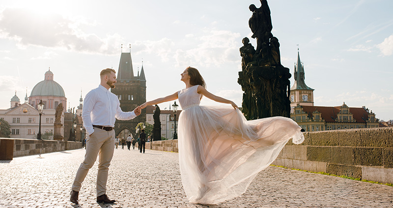 A photo of a newlywed couple dancing on a Charles Bridge in Prague.
