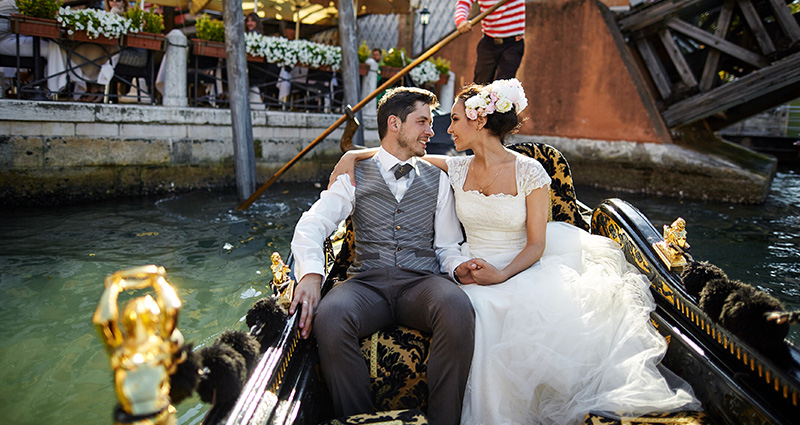 Een foto van een bruidspaar dat op een gondel in Venetië drijft.