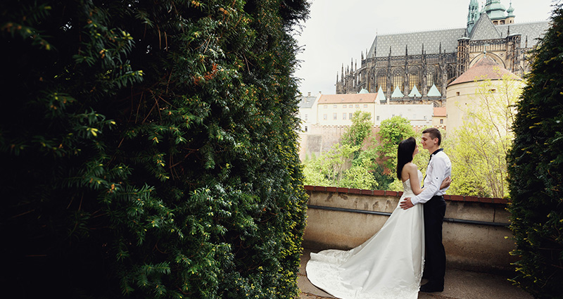La foto di una coppia di sposi a Praga; sullo sfondo è visibile un castello.