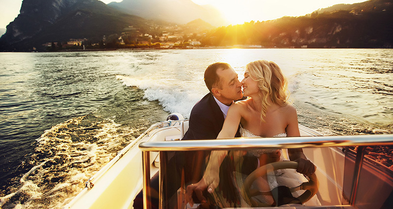 Een foto van een kussende bruidspaar op een motorboot.