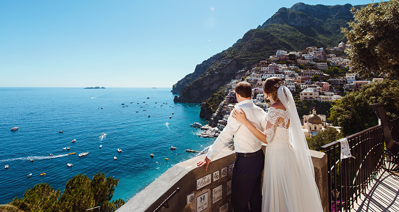 La foto di una coppia di sposi che guarda il mare su una terrazza panoramica ad Amalfi.