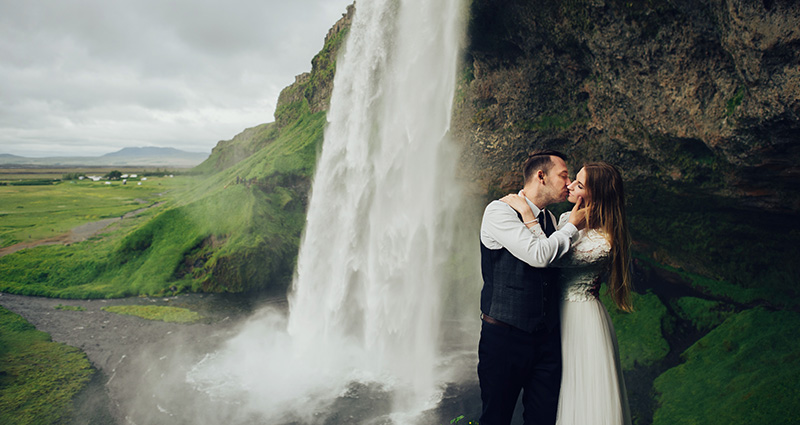 Romantická fotografia nevesty a ženícha s vodopádom v pozadí, Island.