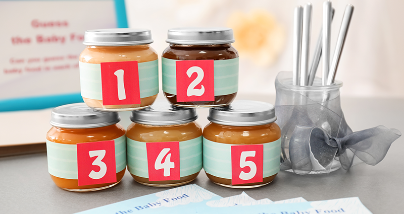 Jars with baby food with covered labels, spoons and pieces of paper to write down the answers.