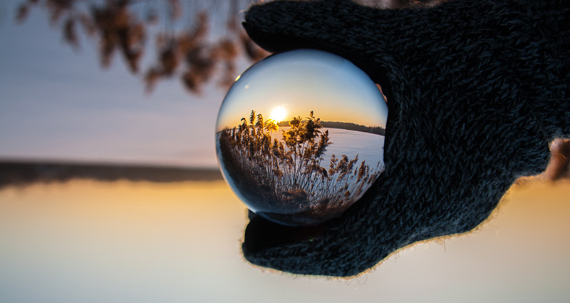 Lake and swards reflected in a ball which is hold by a gloved hand