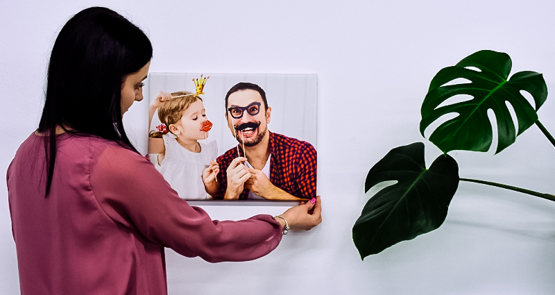 Une femme accroche la toile avec photo d’un père avec sa fille.