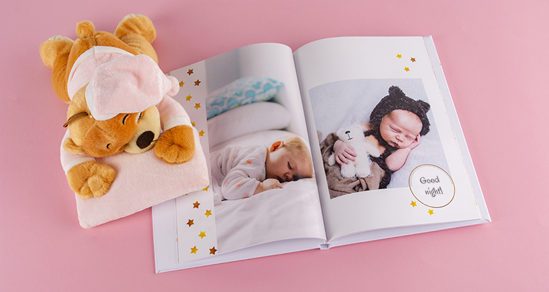 Fotobuch mit Bildern vom Baby-Fotoshooting, daneben ein Kuschelbär. 