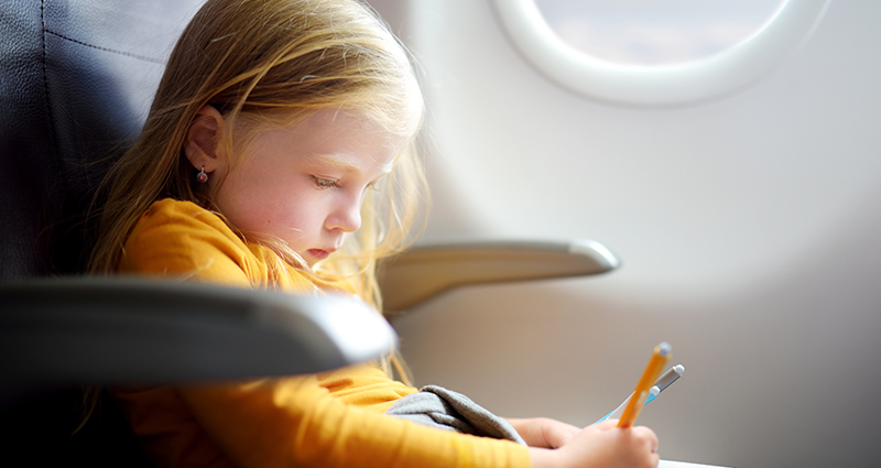 Nuotrauka mergaitės, kuri žaidžia skrydžio lėktuvu metu.