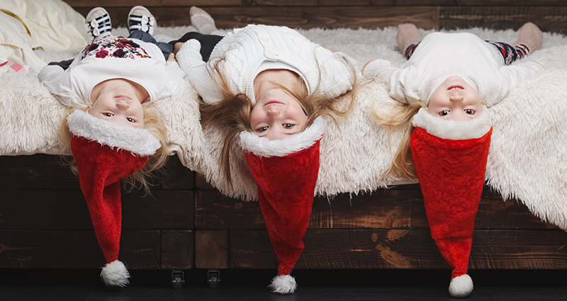 Trys mergaitės, dėvinčios Kalėdų senelio kepures