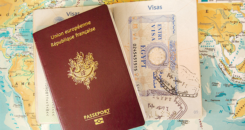 Dos pasaportes, uno abierto, un mapa en el fondo. 