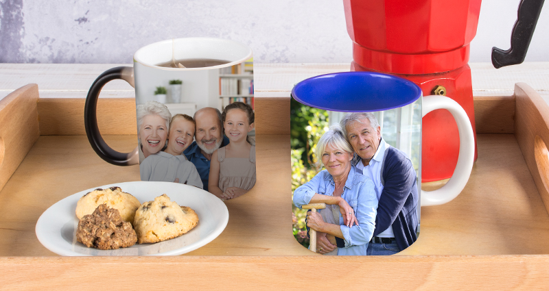 Two personalised photo mugs on a wooden tray, cookies on a plate and a red moka pot next to it.