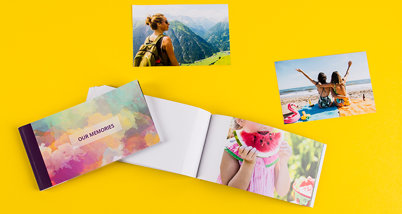 Zwei Sharebooks, eins offen, daneben ein Sharebook mit dem Insta Color-Cover, über den Sharebooks Urlaubsfotos.