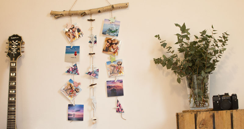 Photos hanging on twine attached to a branch.
