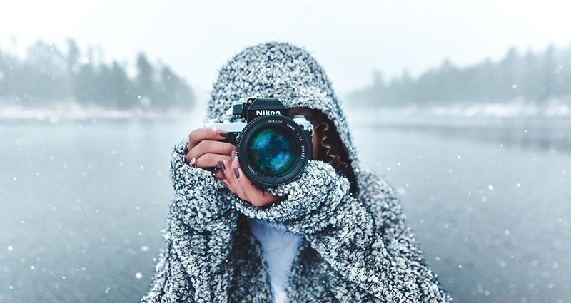 Eine Frau macht ein Foto mit der Kamera mit dem See im Hintergrund