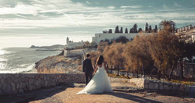 Fotografia nevesty a ženícha na ceste pri skalnatom pobreží.