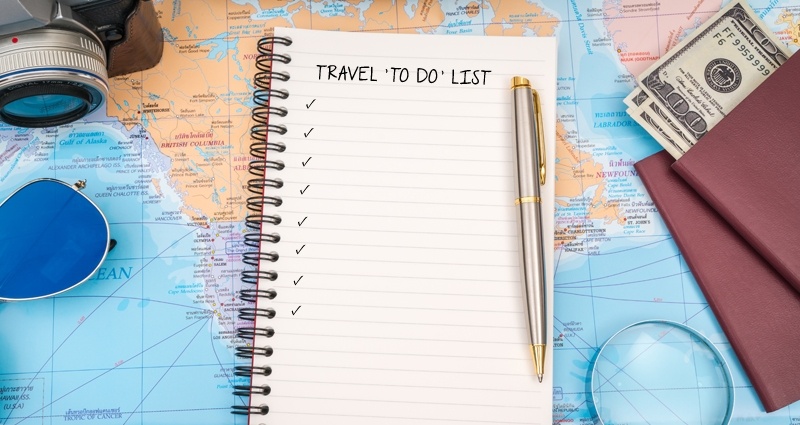 Spiraalvormig notitieboekje, paspoort, geld, camera en zonnebril, kleurrijke kaart als achtergrond