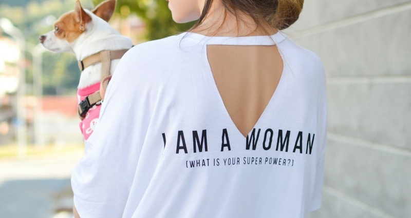 "I'm a woman, what's your superpower?" - Aufschrift auf dem Rückenteil eines weißen T-Shirts, das eine junge Frau anhat / Foto von  Pete Bellis auf Unsplash