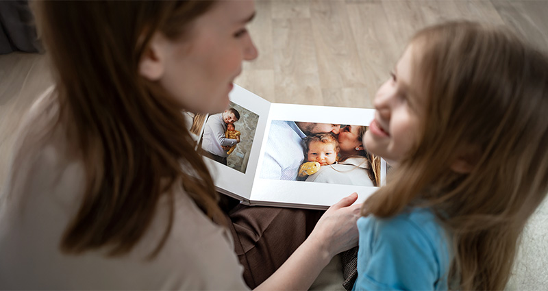 Mother and daughter are looking through a photo book as a Christmas present.