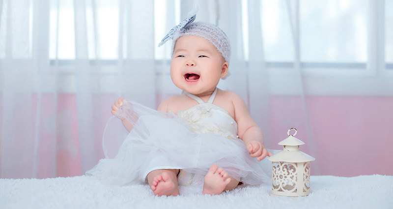 A babbling baby girl, dressed in a blue dress and band.Una niña que charla en un vestido acampanado y una banda para el cabello. 