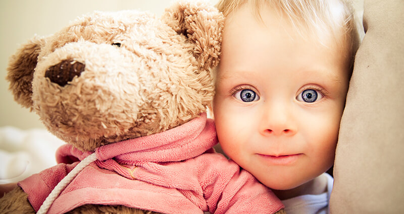 Un niño con ojos grandes y un osito de peluche.