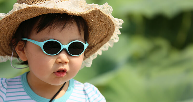 Un garçon avec le chapeau et les lunettes bleus.