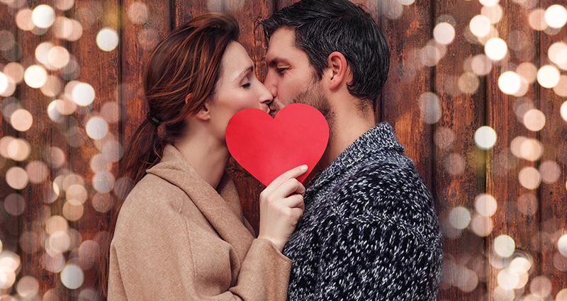 Een verliefd stel kust met een hart gepersonaliseerde valentijnscadeaus
