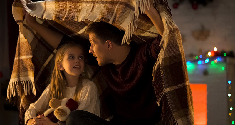 Papa speelt met zijn dochter in een tent van dekens