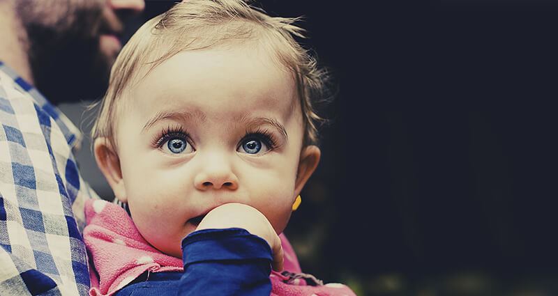 Una niña con ojos azules en los brazos de su papá.