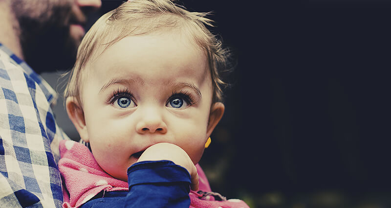 Une fillette aux yeux bleus  dans les bras de son père.