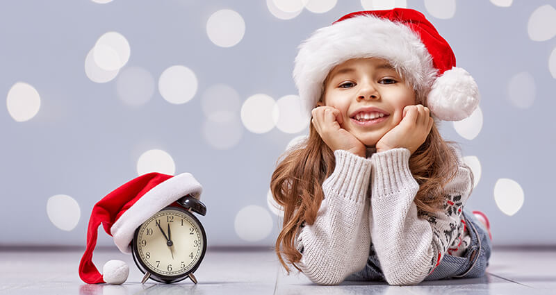 A girl in a Santa’s hat, laying on the floor.