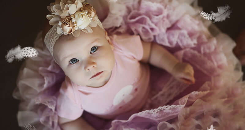 Una niña en una banda con flores y un vestido de princesa.