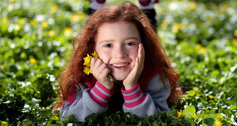 A girl laying on the grass, in a park.