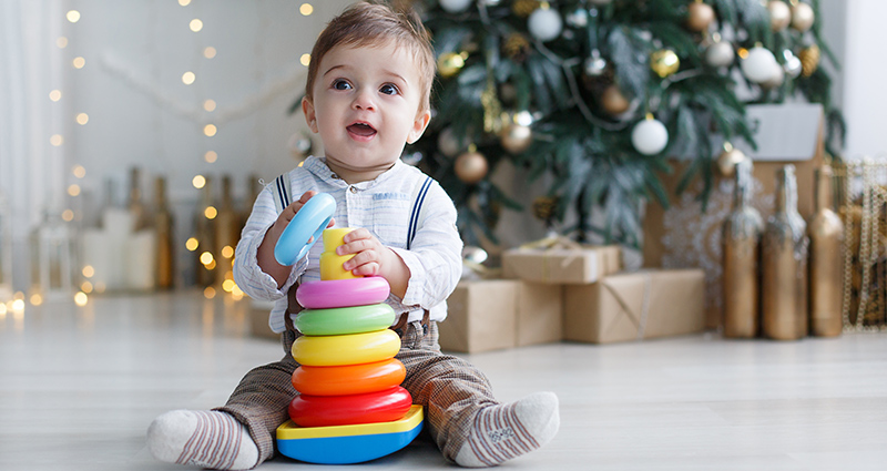 A little boy in an elegant shirt sitting in front of a Christmas tree