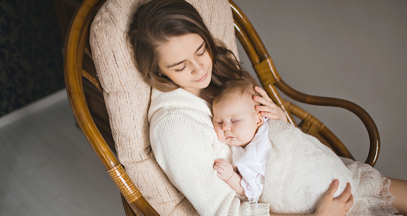 Mamá sentada en un sillón con el niño dormido