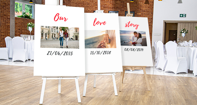 Une photo de trois toiles photo sur des chevalets qui présentent des photos de différentes étapes de vie de jeunes mariés avec des dates, au fond des tables rondes sur la salle de mariage.