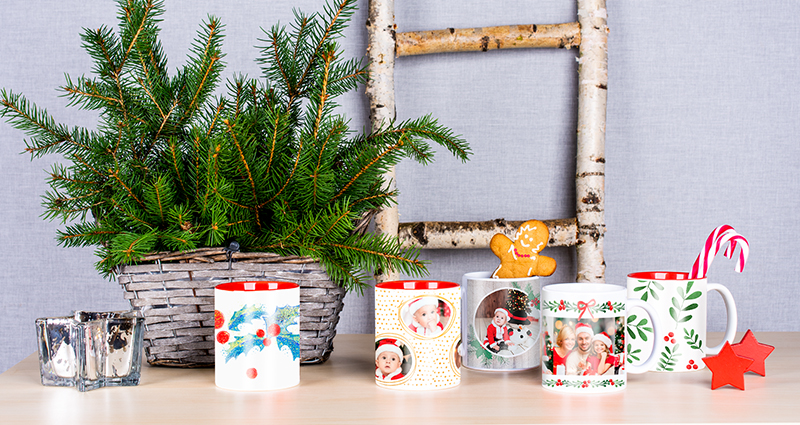 De foto laat verschillende kerst sjablonen zien. Op de achtergrond zijn: een kandelaar en groene takken te vinden. In sommige mokken bevinden zich lekkernijen.