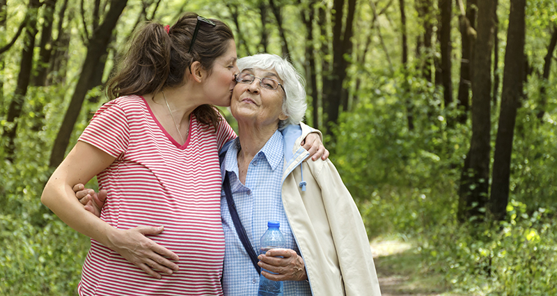 A pregnant woman hugging her grandmother