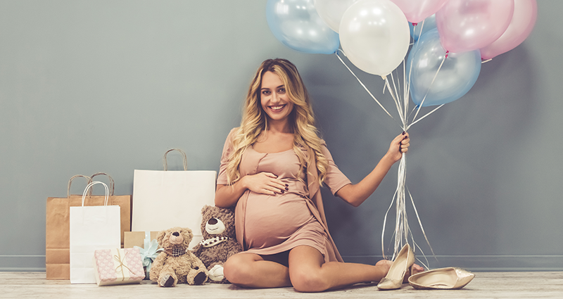 Nėščia moteris su dovanomis ir balionais rankoje