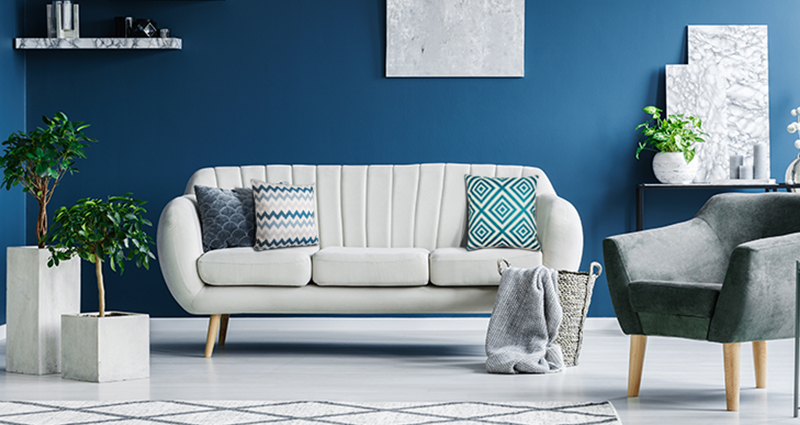 A sofa with square cushions, geometrical lamps and plants in square pots