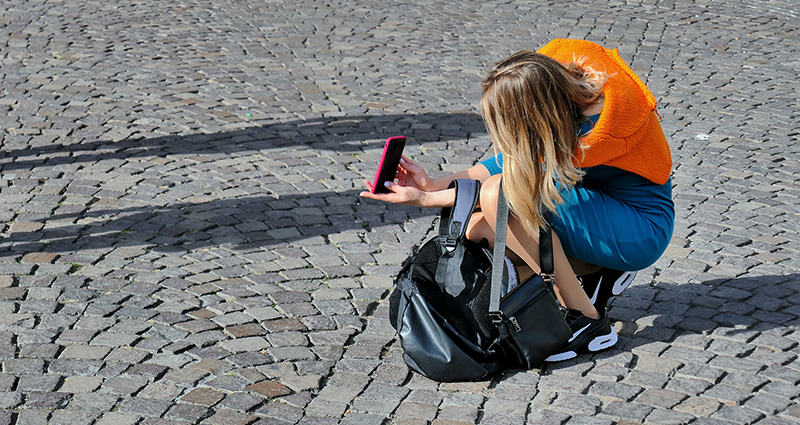 Eine Frau, die aus Sicht eines Frosches, zwei Personen mit dem Smartphone fotografiert. 